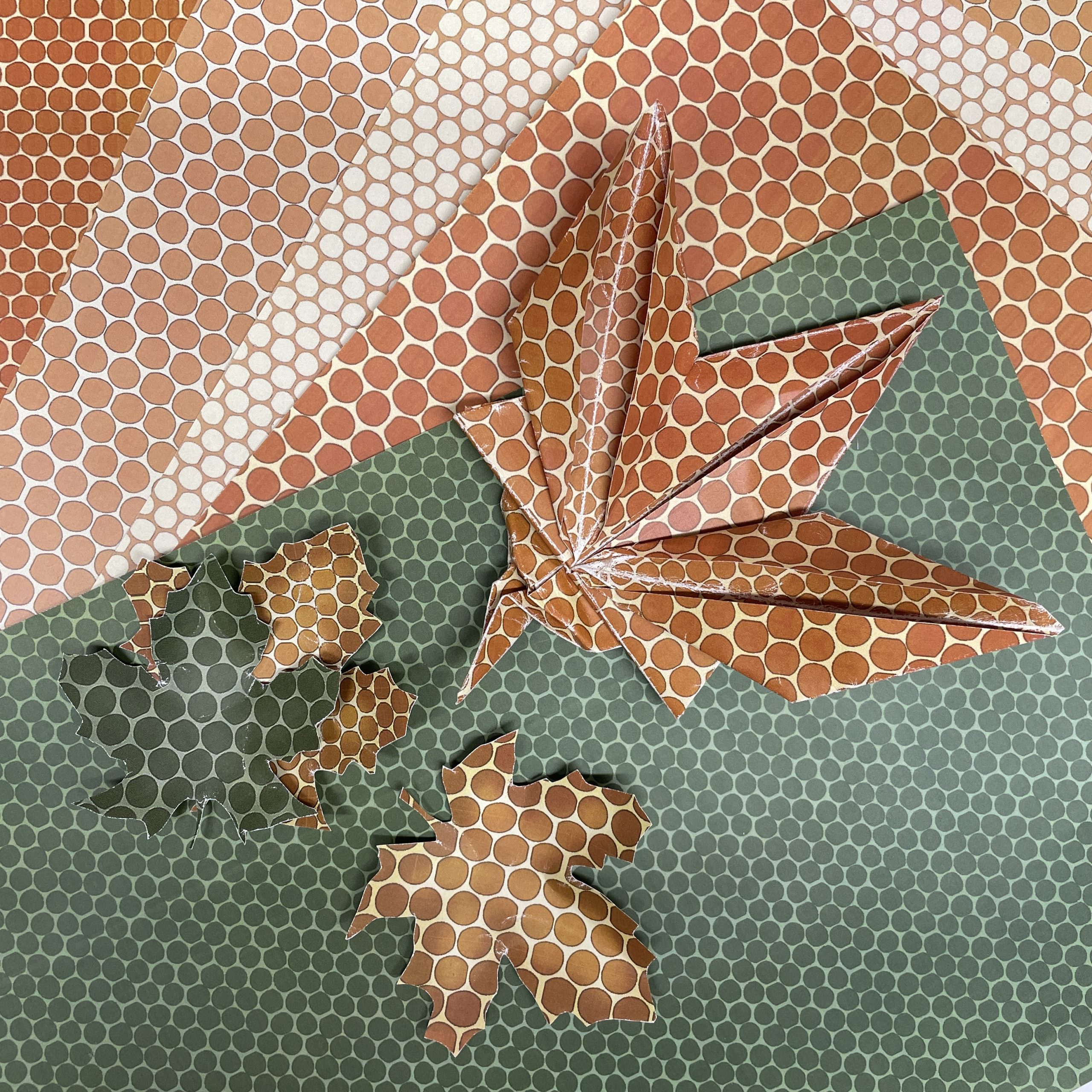 Image of A4 colored pattern paper and a origami maple leaf and cut-out maple paper leaves.
